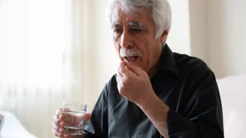 Pharmacy: senior man taking oral medication 1297539553