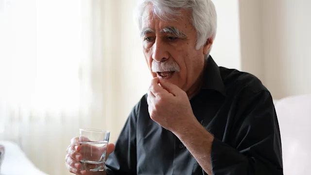 Pharmacy: senior man taking oral medication 1297539553