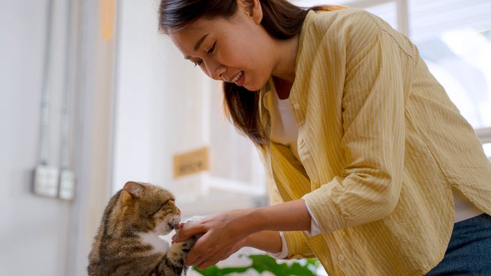 Woman giving medication to her cat.
