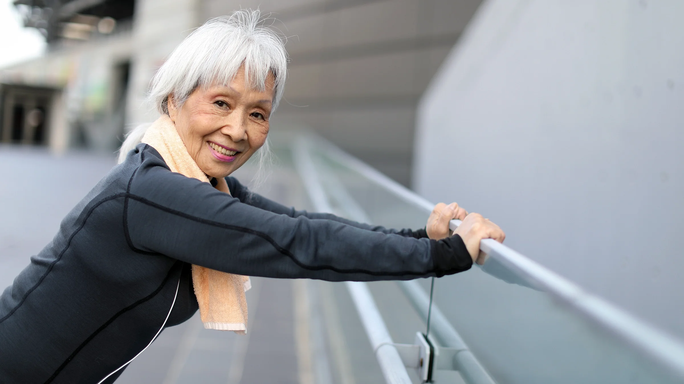 A senior woman is shown stretching outdoors.