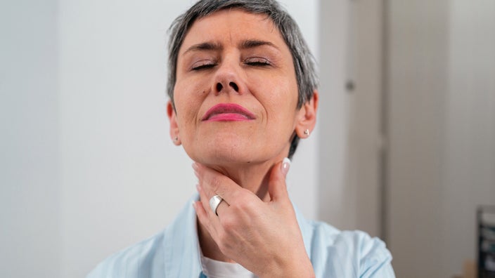 A sick person touching their swollen neck lymph nodes.
