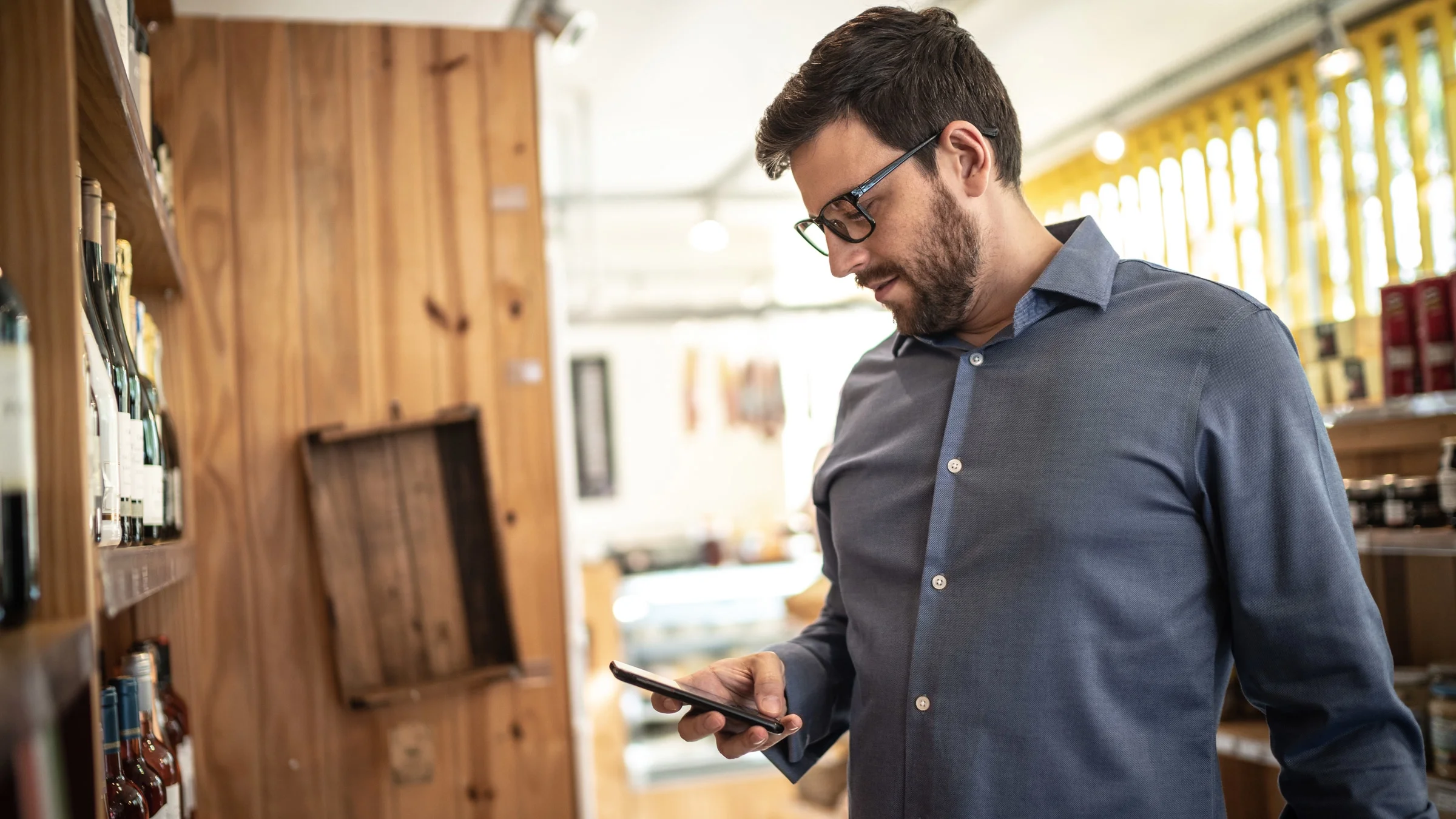 A person using their phone in a wine shop.