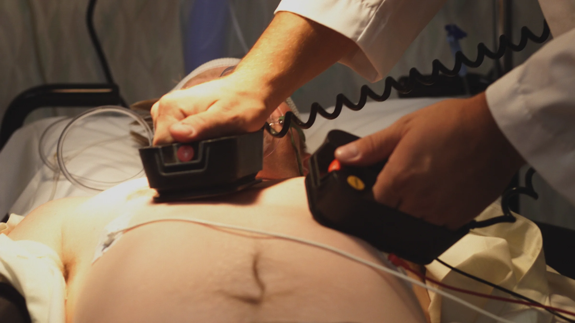 Cropped close-up of a person using a defibrillator on an adult in the hospital.