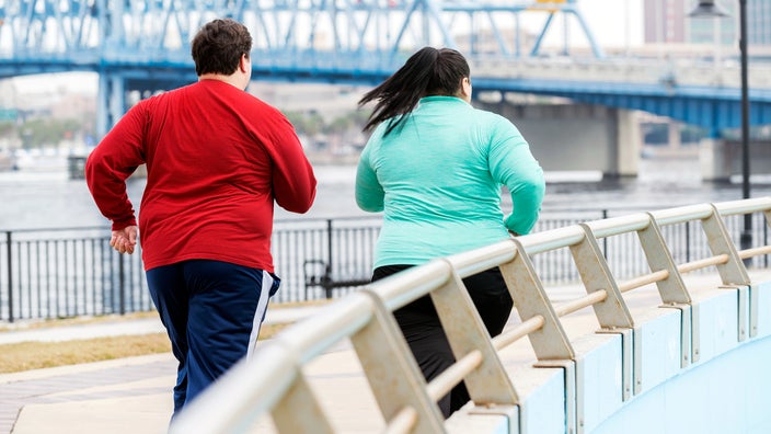 Rear view of man and woman jogging in the city.