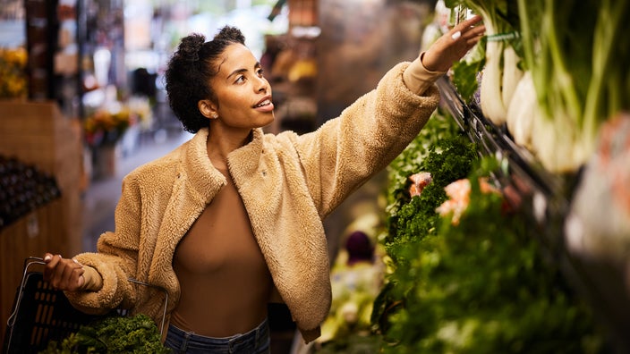 A woman shops for fresh vegetables in the produce aisle.