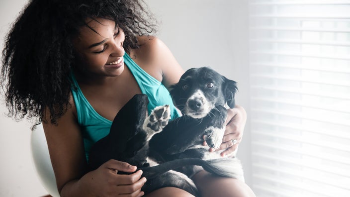 Woman smiling with dog on her lap at home.