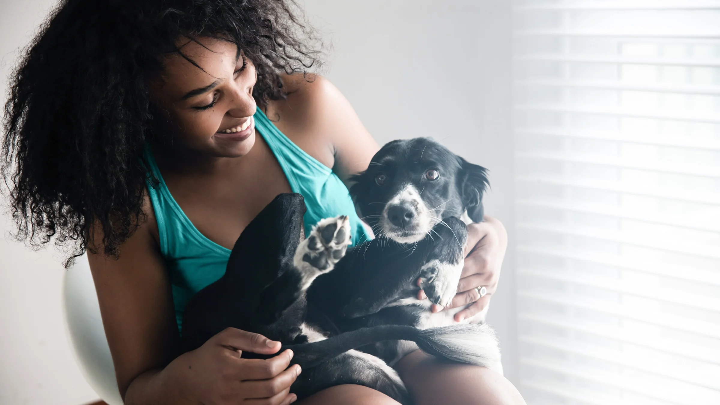 Woman smiling with dog on her lap at home.
