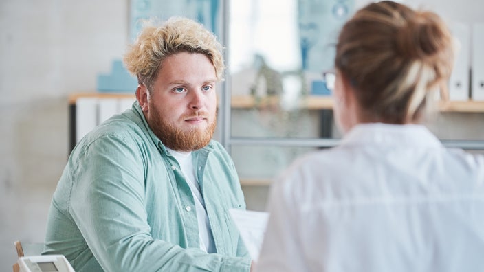 Young man with bleach blond hair consulting with his provider. It looks like a serious conversation.