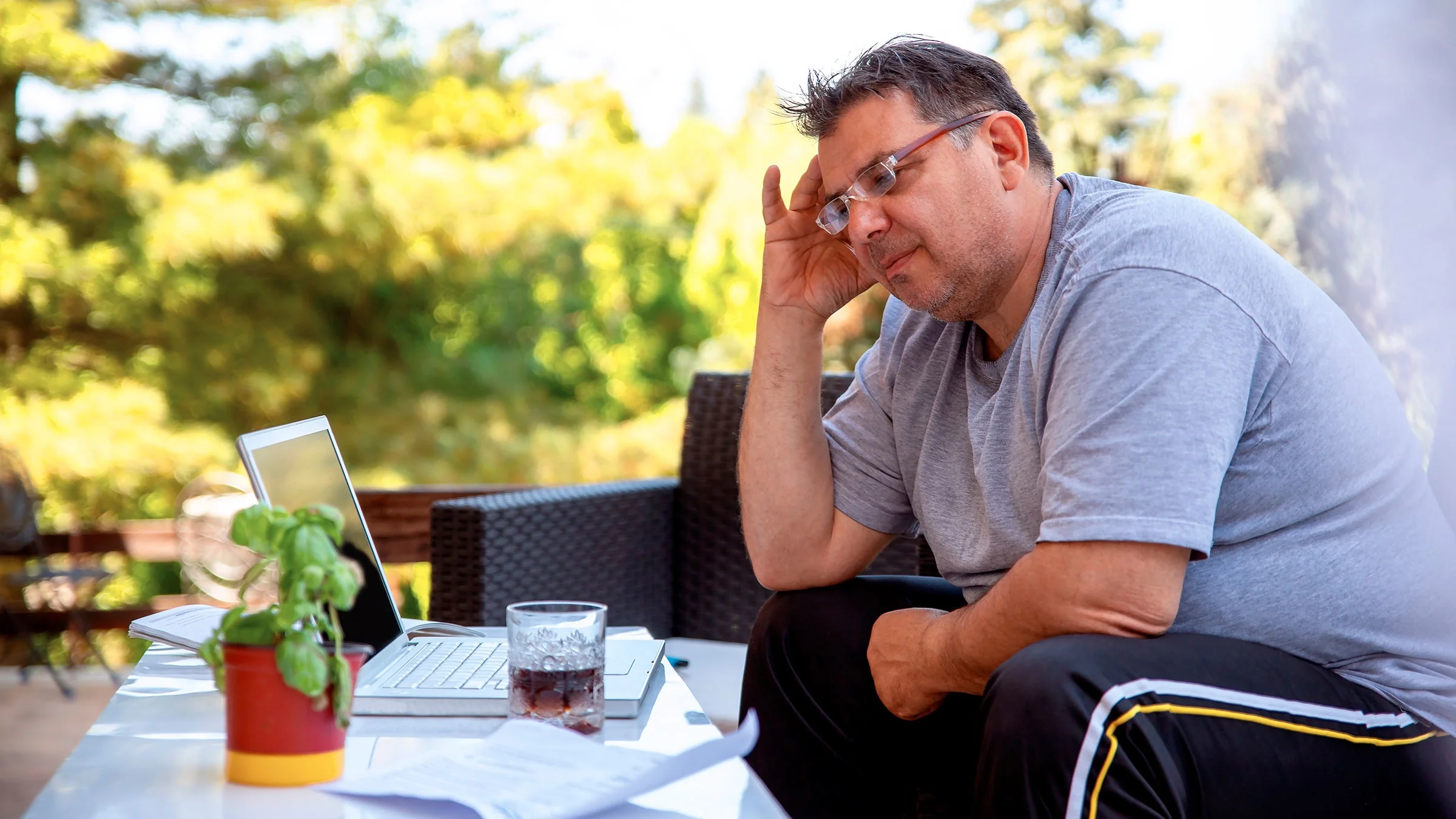 A man does research on his laptop while sitting outside on his patio.