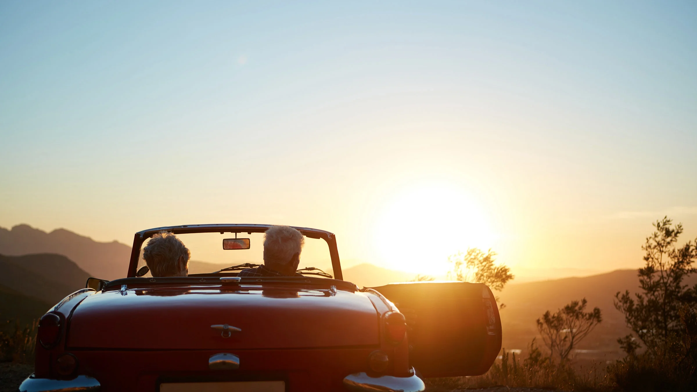 A couple embarking on a trip in a convertible.