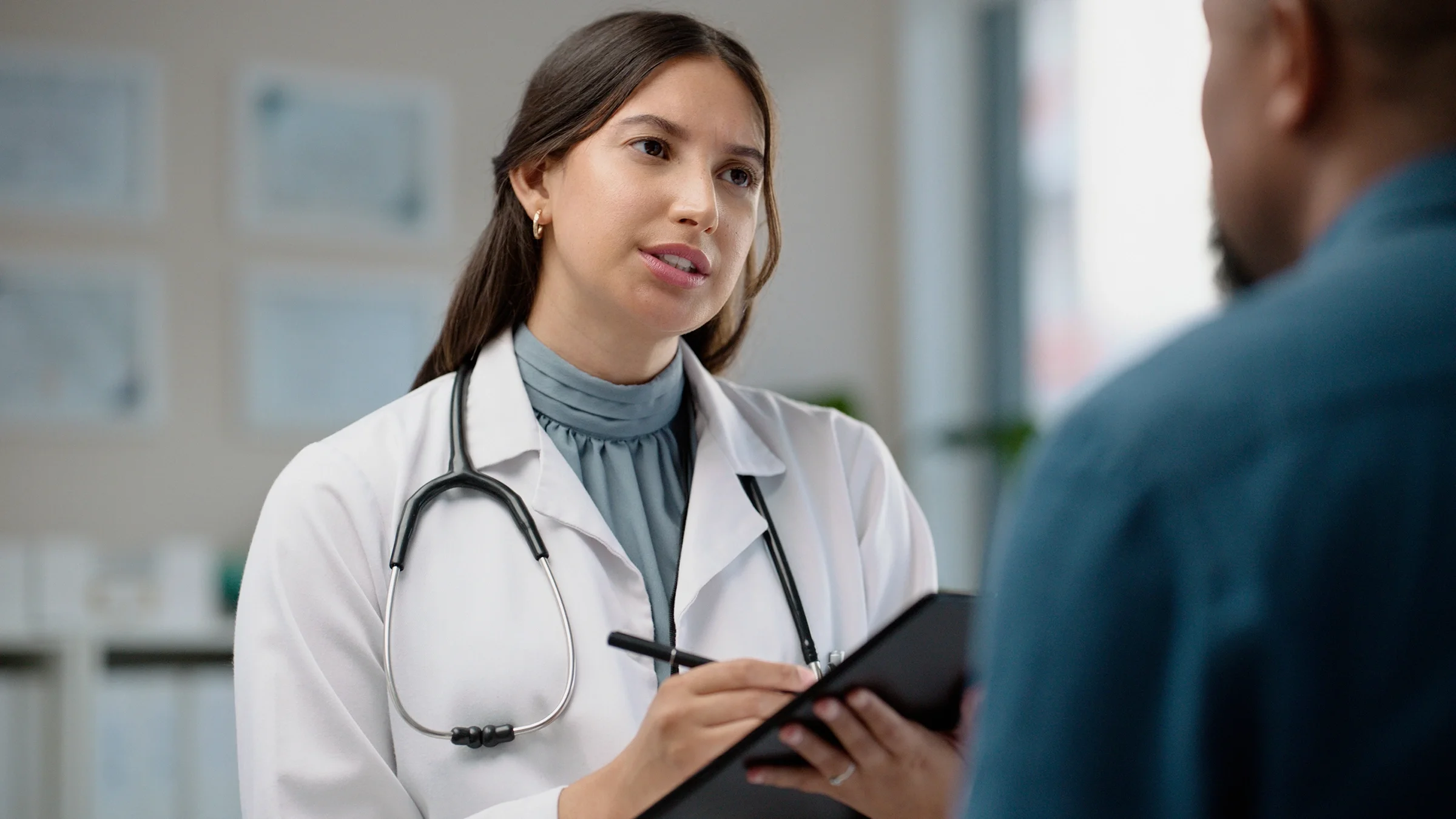 Medical professional with a clipboard talking to a patient.