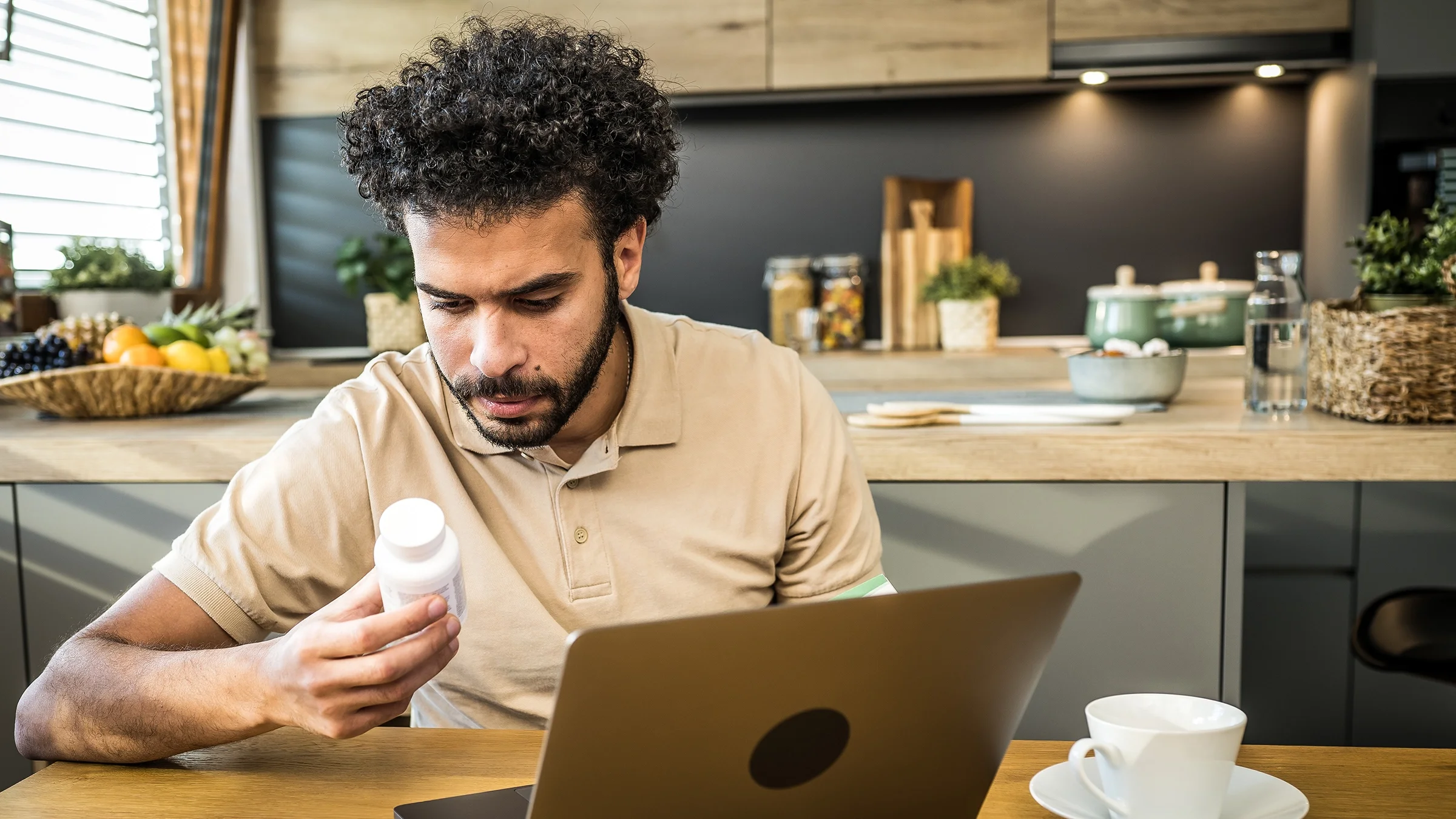 A man studies the label of a medicine bottle at home.