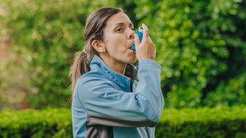 Health: Asthma: woman using inhaler outside-1332789288