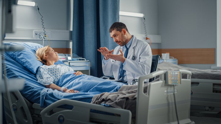 A provider explaining something to a person in their hospital bed.
