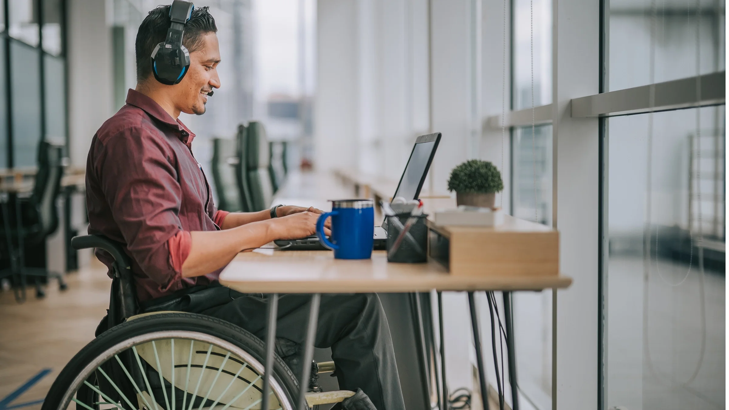 Man in wheelchair working at his desk and smiling.