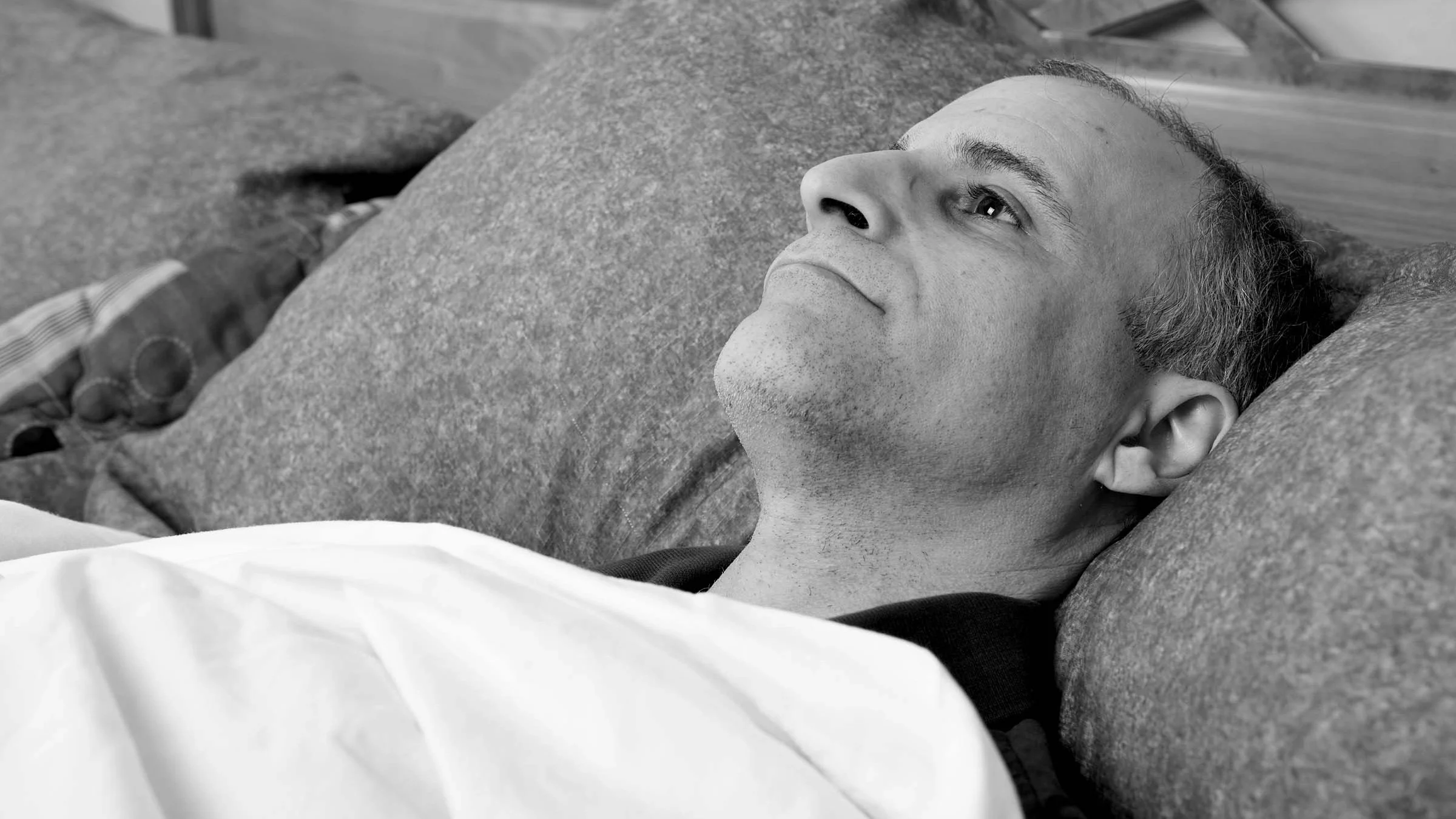 Man laying in bed face up wide awake.