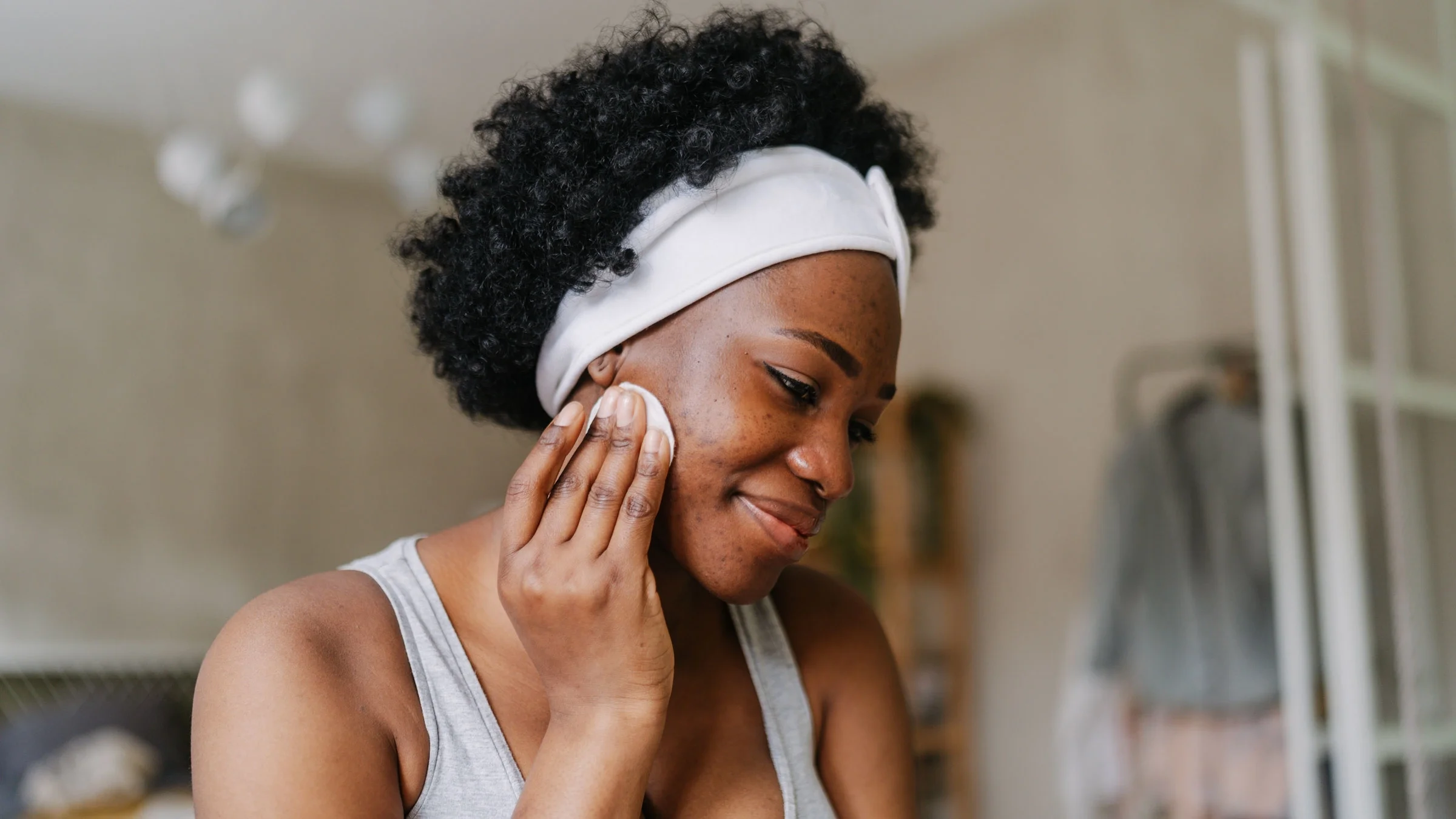 A Black person with hyperpigmentation doing their skincare routine.