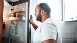 A man looks inside his open refrigerator. 
AleksandarGeorgiev/E+ via Getty Images