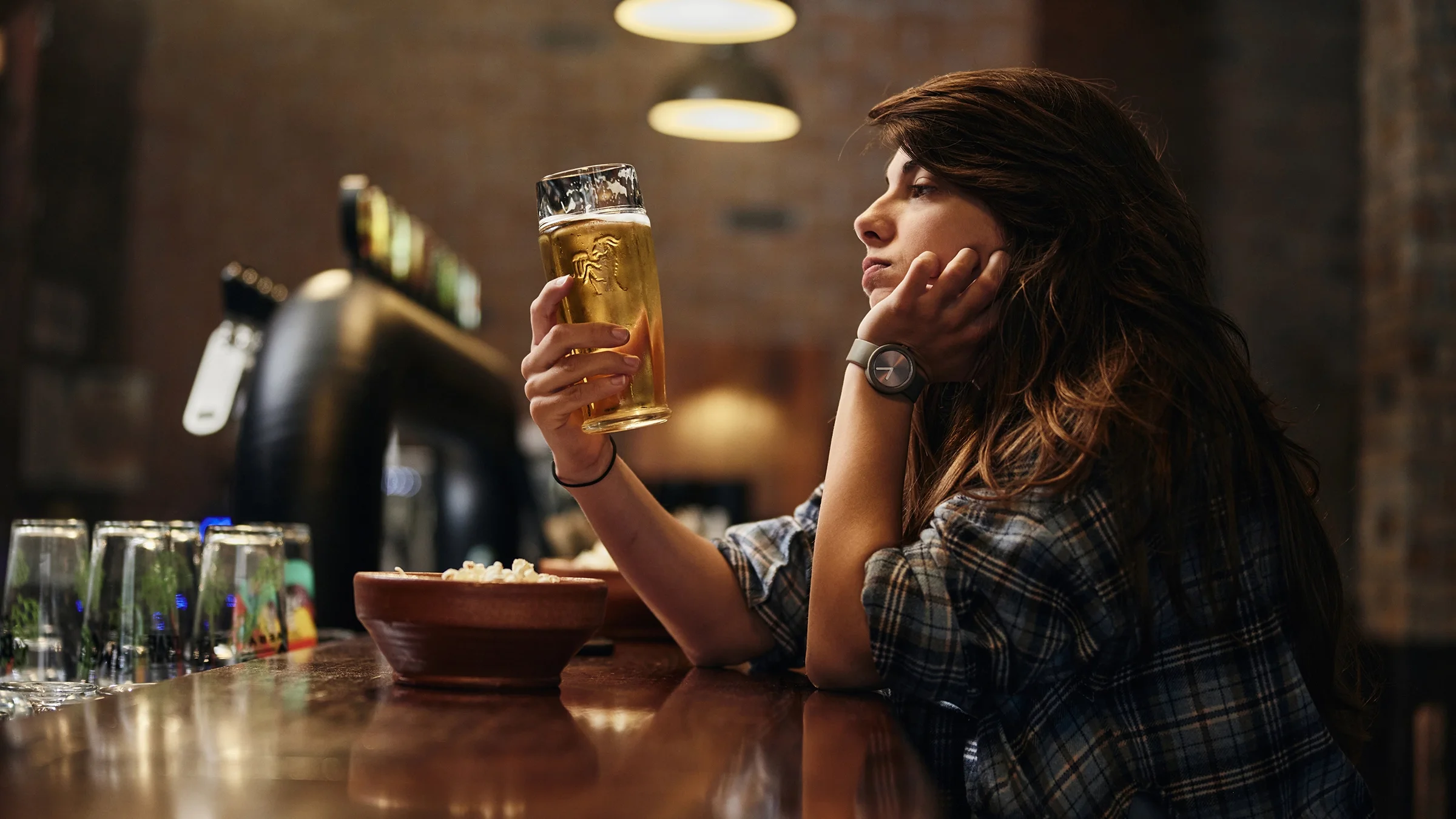 A woman drinks a beer alone at a bar.