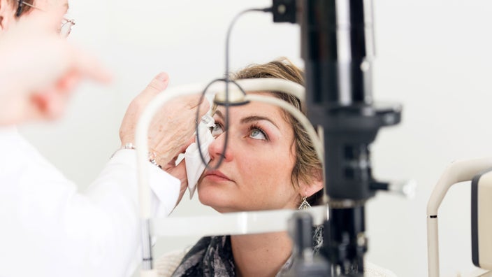 A patient has her eye examined by a doctor.
