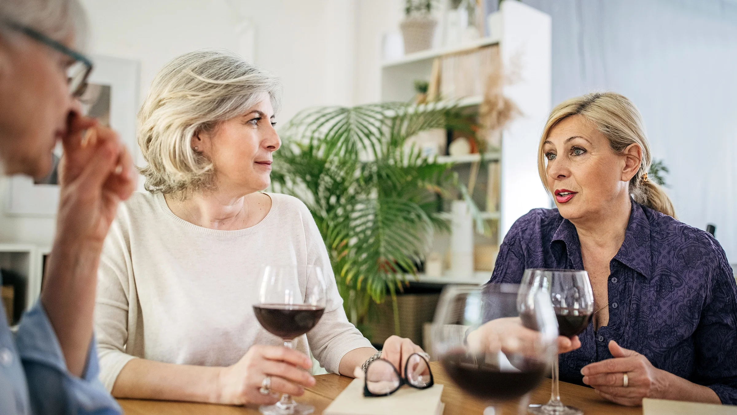 Three women enjoy a glass of wine and conversation together.