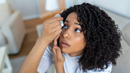Young woman putting in eye drops as she tilts her head back.
stefanamer/iStock via Getty Images