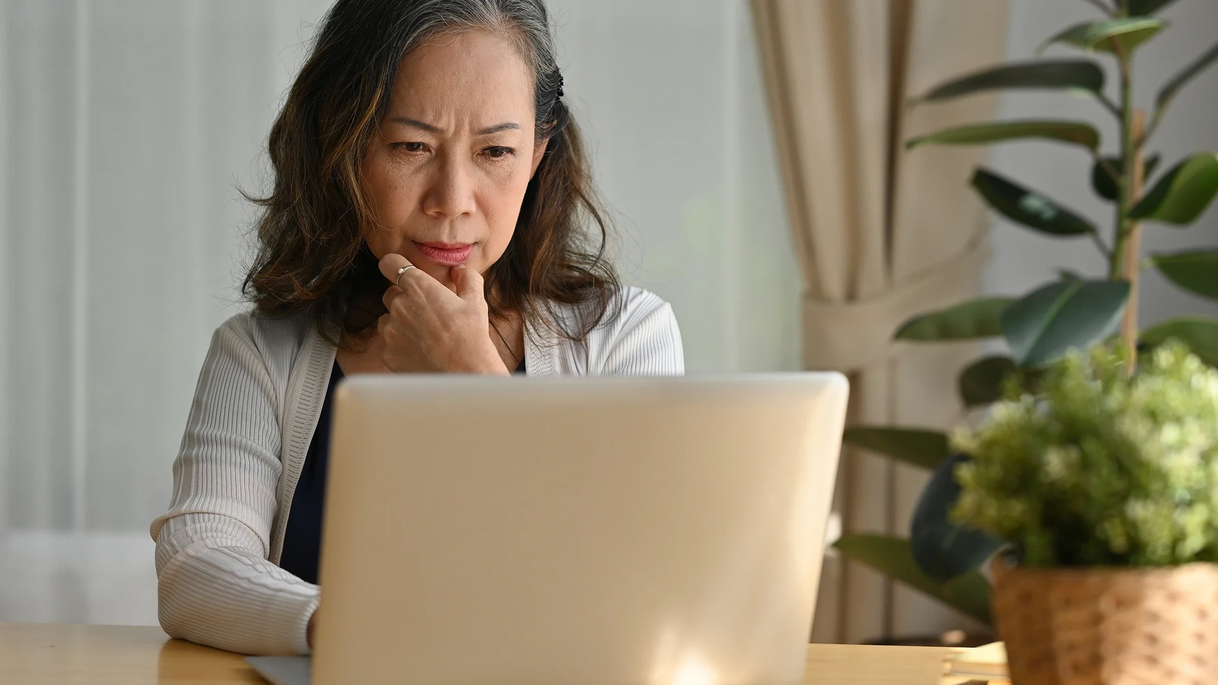 A woman appears concerned while using a laptop.