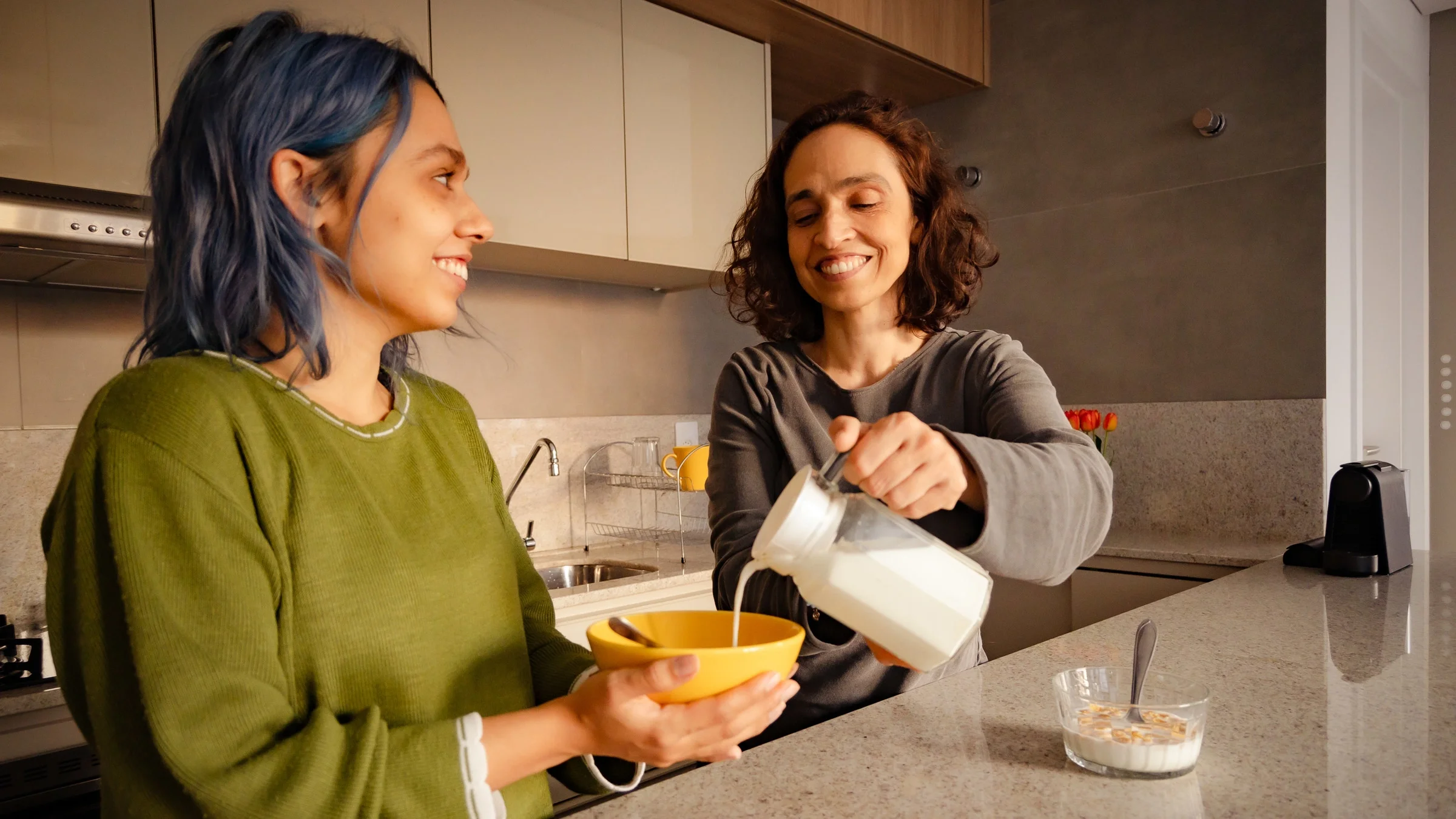 A parent pouring milk into their child's cereal.