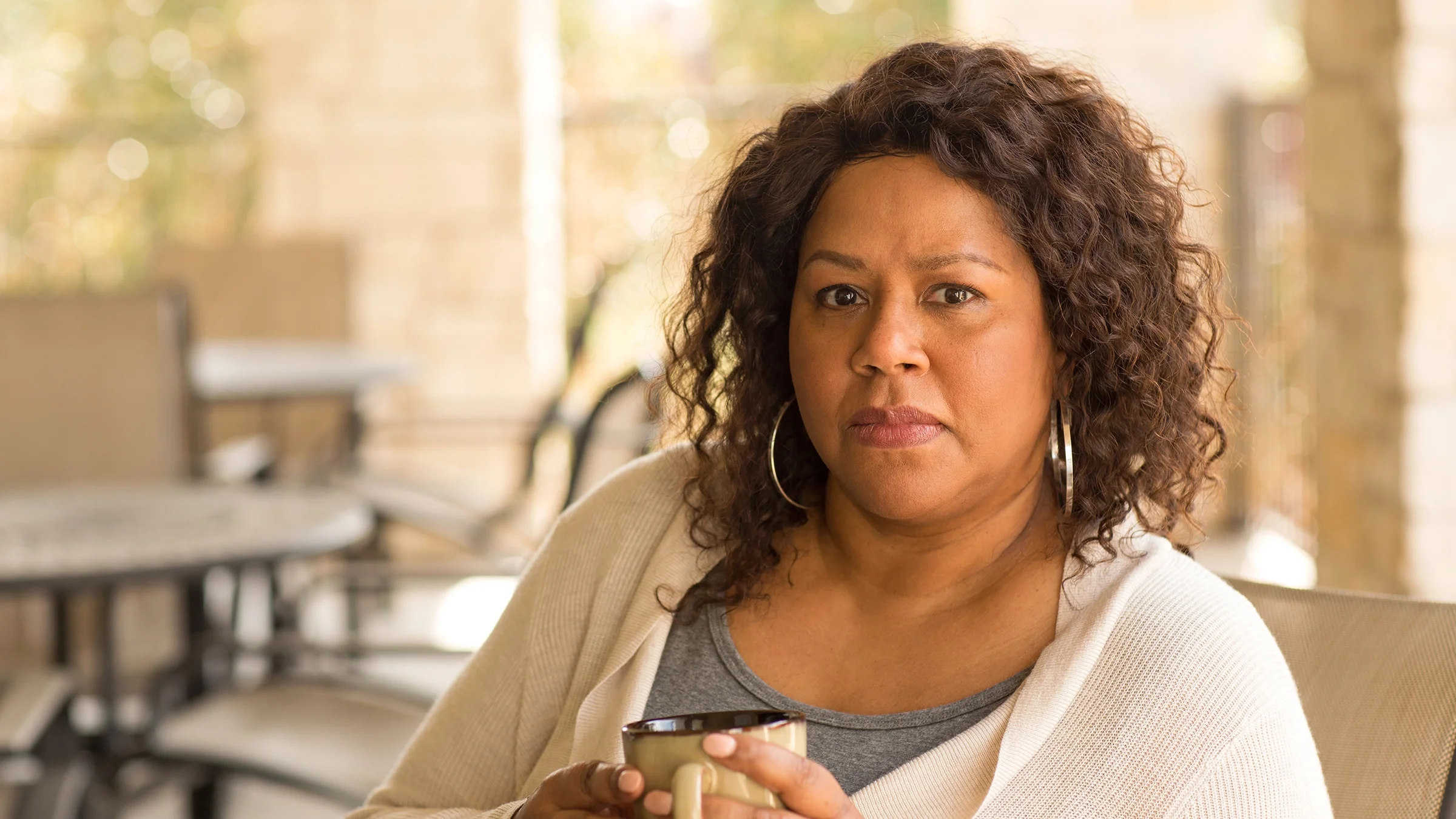 Portrait of a serious woman as she sits outside on a patio.