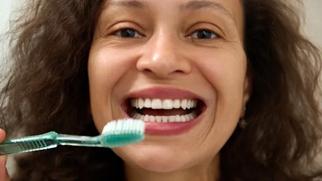 Dental care: woman smiling and holding toothbrush 1933000635