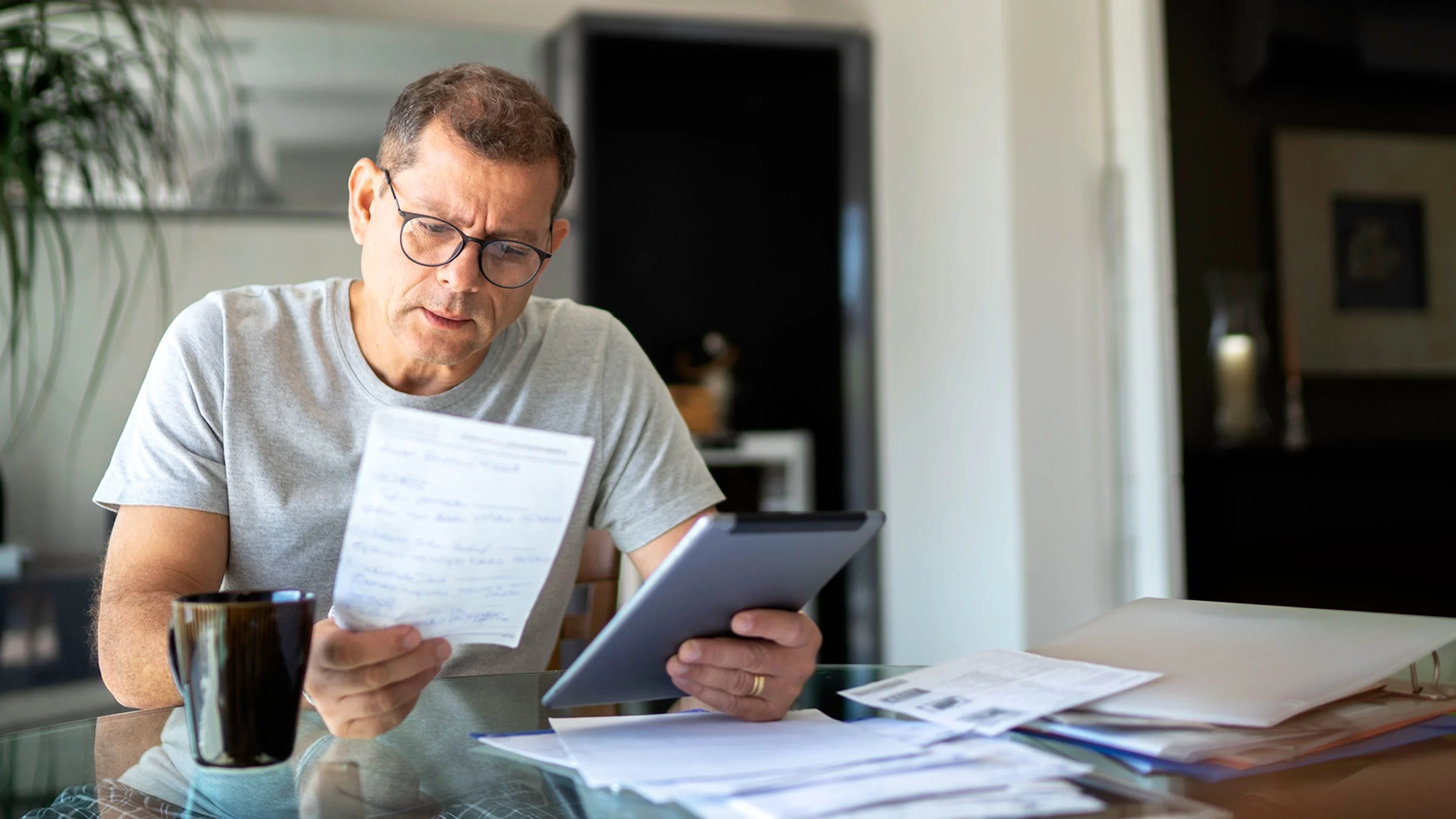 A man is reviewing paperwork at home.