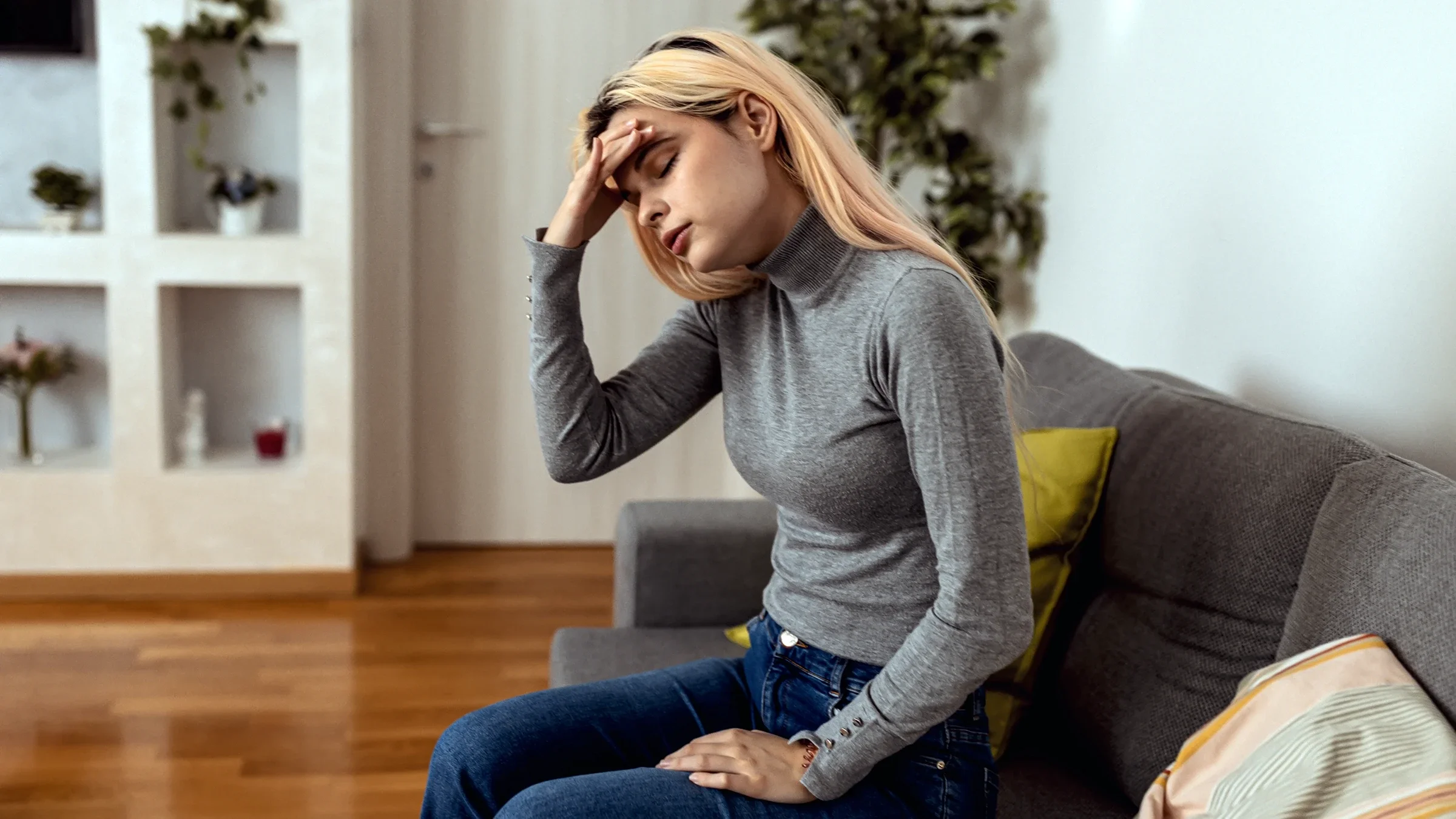 A woman holds her head while dealing with a migraine.
