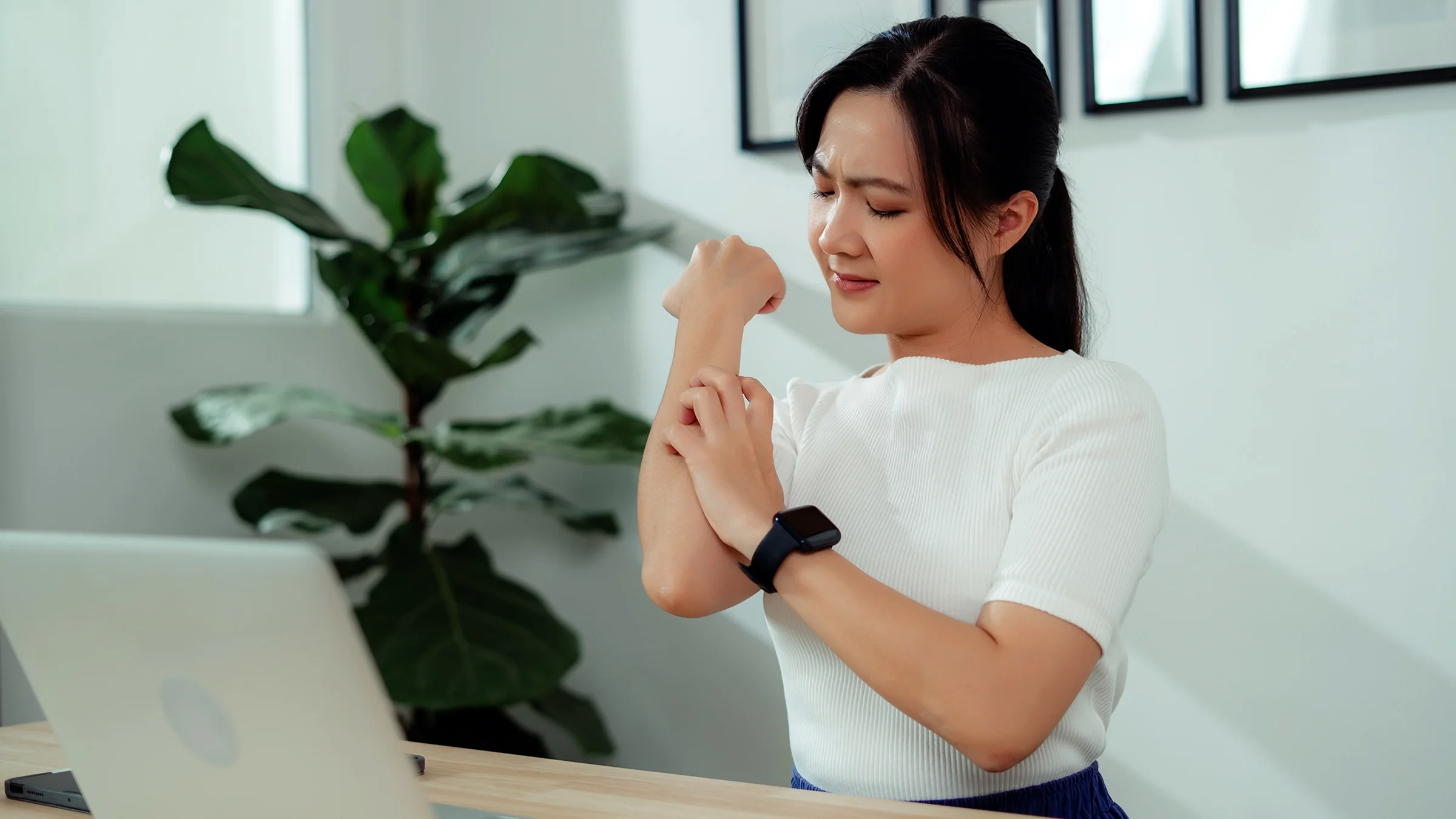 A woman scratches her arm.