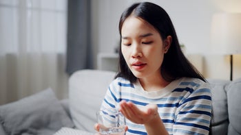 Trintellix: woman holding a pill and glass of water 2166843137