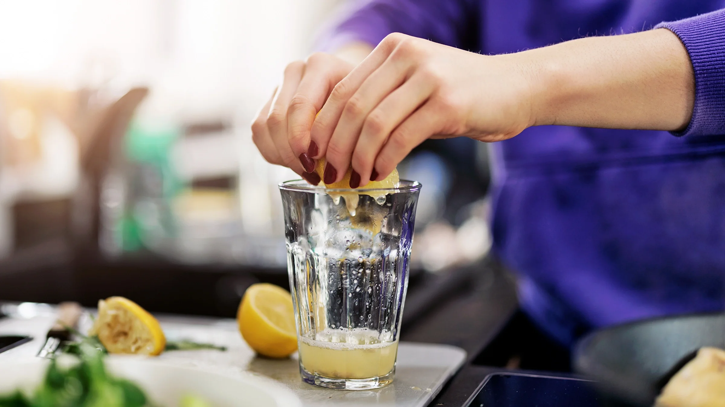 A woman squeezes a lemon. Lemon juice is a drink that can help prevent kidney stones.