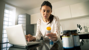 Health: woman reviewing prescription bottle 858721980