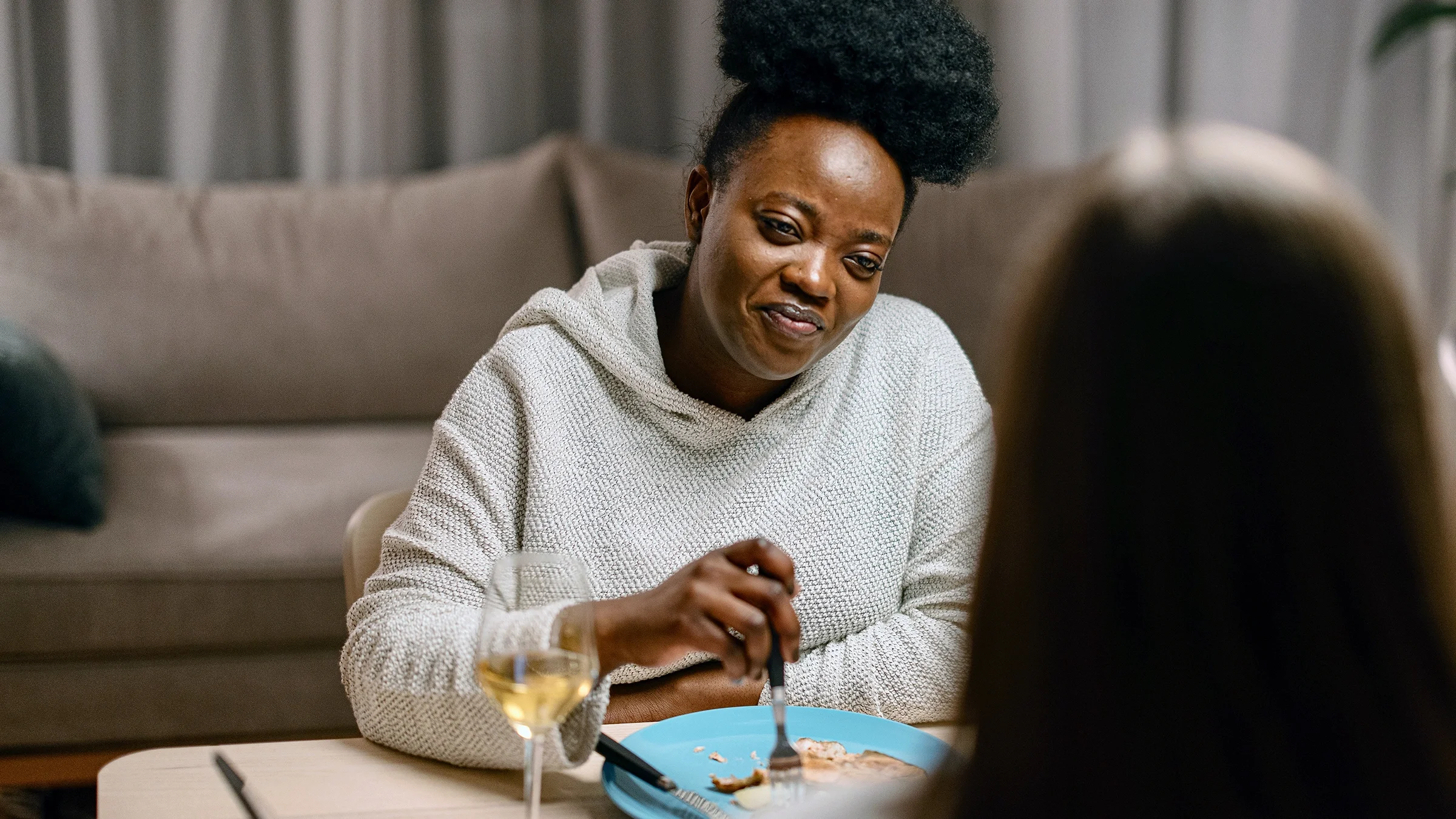 A woman has dinner and a glass of wine with a friend.