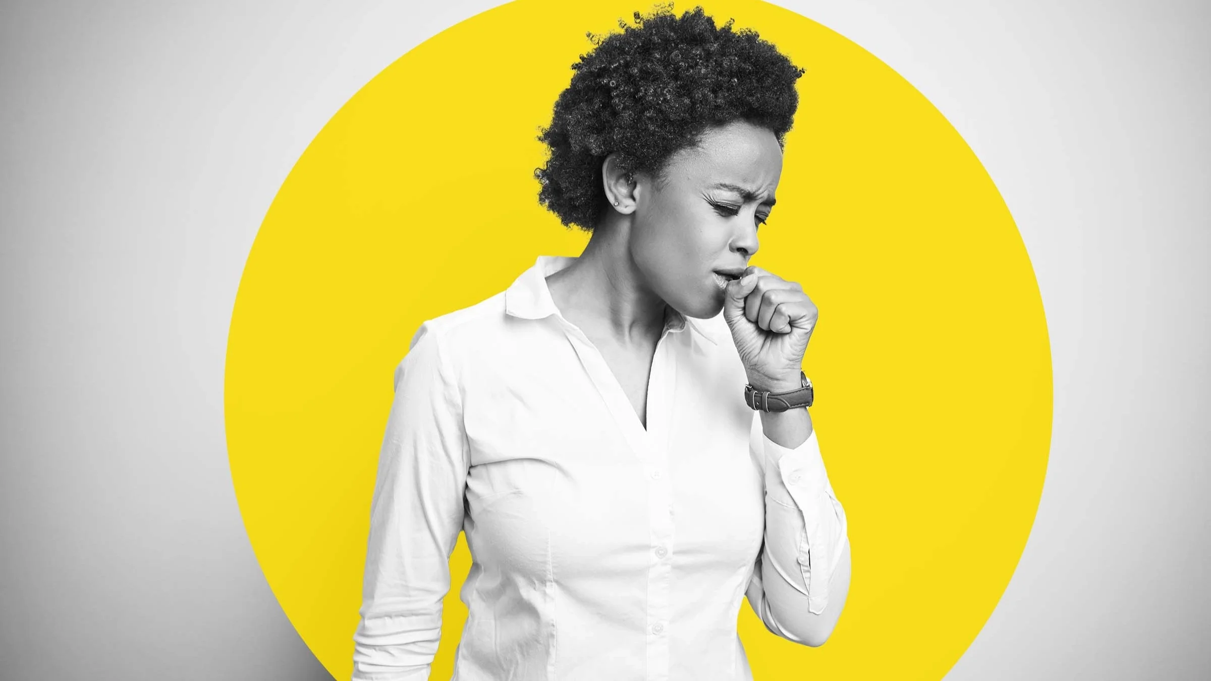 Black and white portrait of a young woman with short curly hair coughing. Her eyes are squinted and her fist is in front of her mouth. There is also a large yellow circle graphic added behind her.
