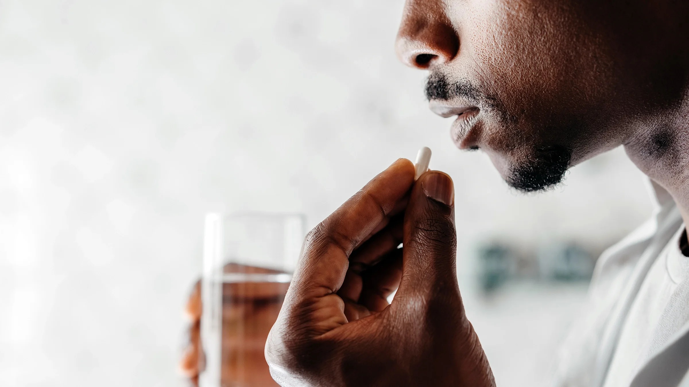 A man prepares to take a pill with a glass of water.