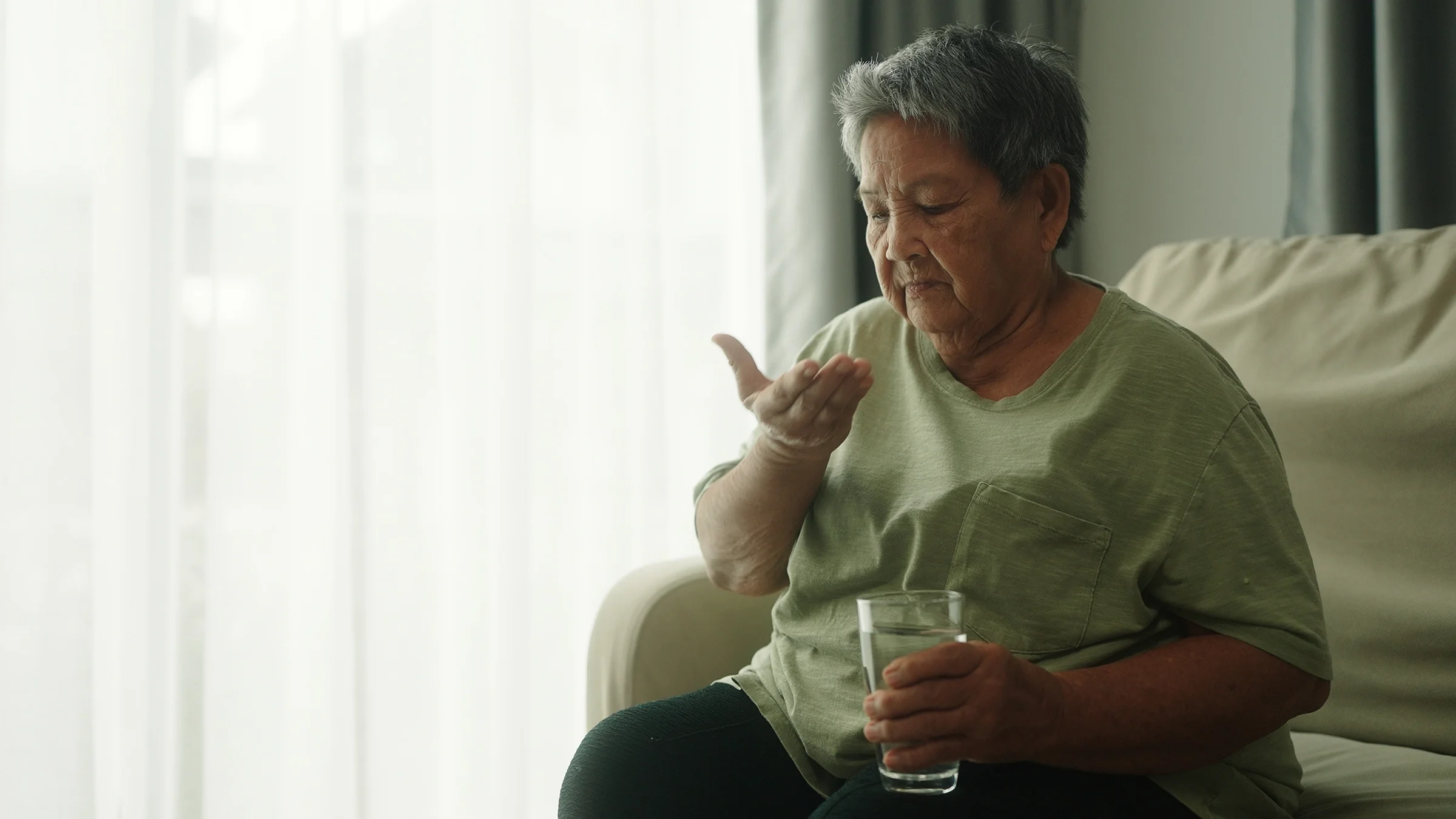 A woman is pictured taking a pill at home.
