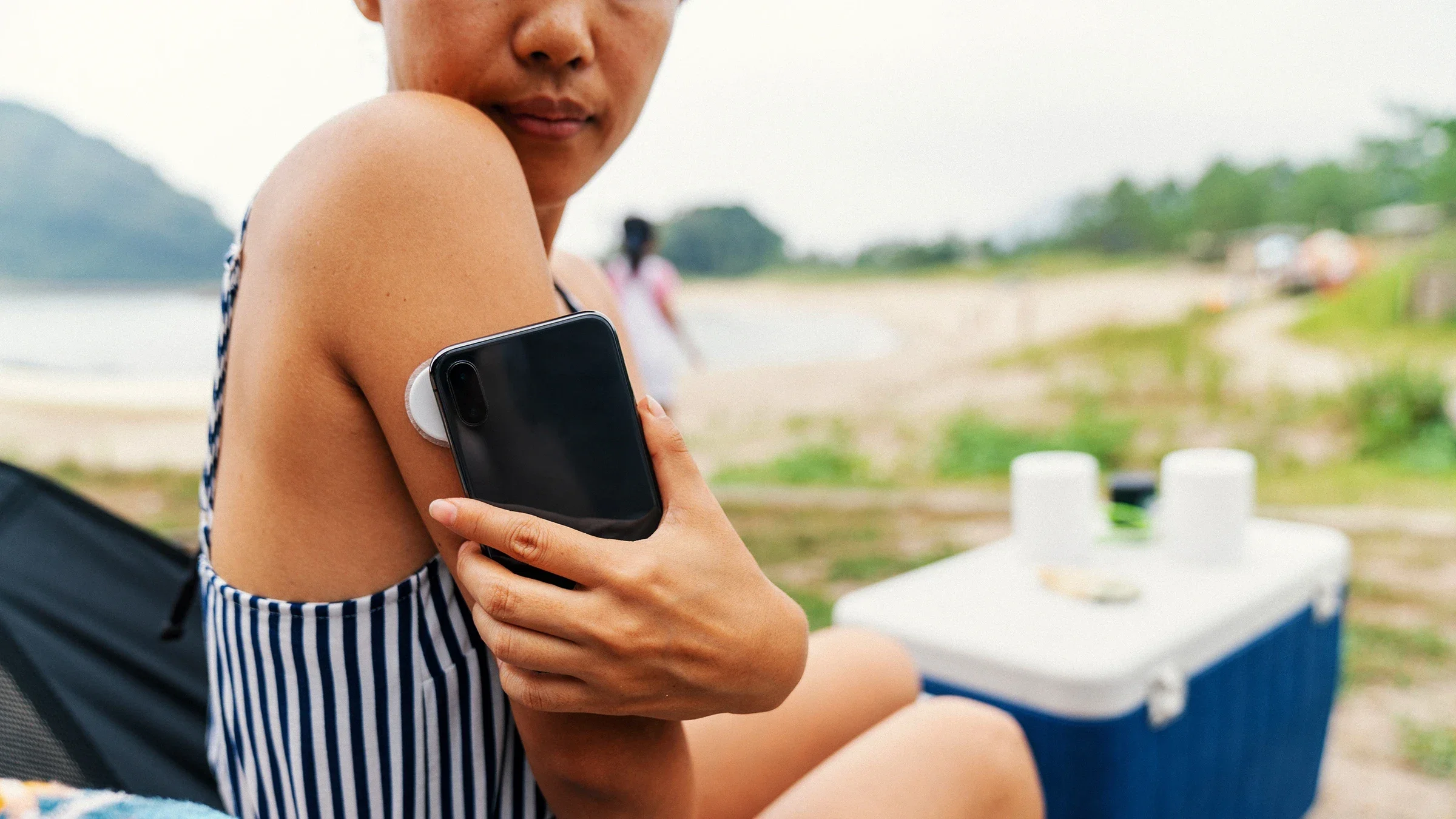 A woman uses her phone to check her blood sugar level.
JGalione/E+ via Getty Images