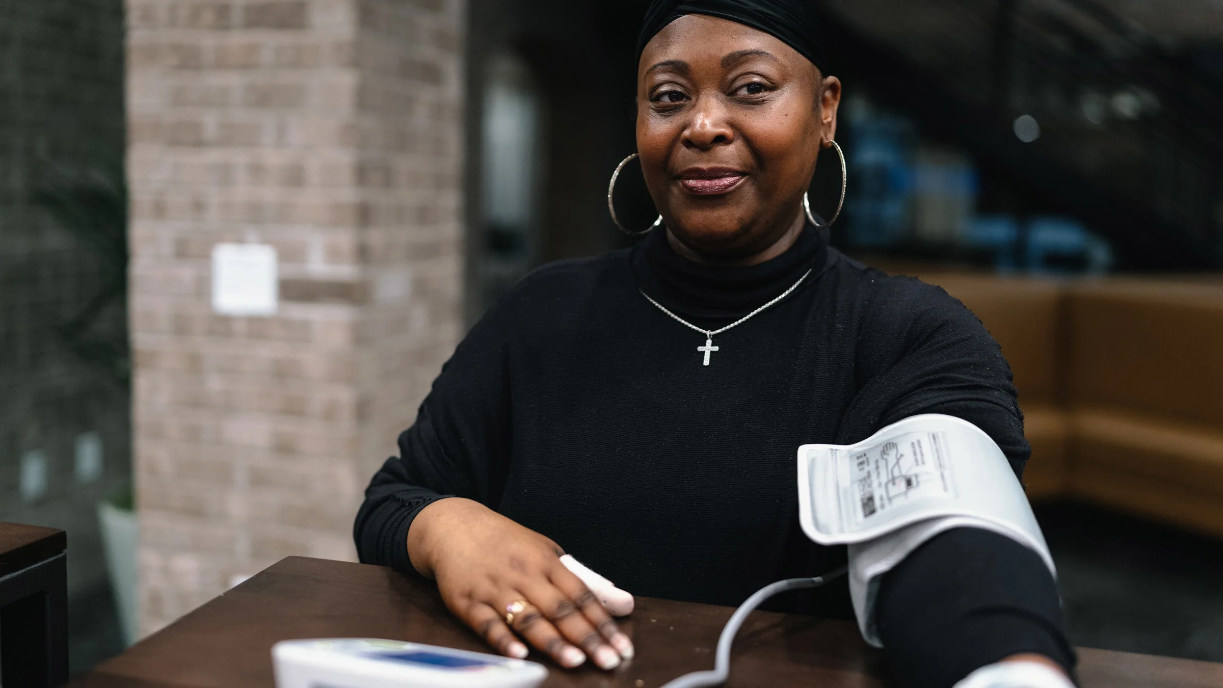 A healthcare provider tests a woman’s blood pressure in an exam room.