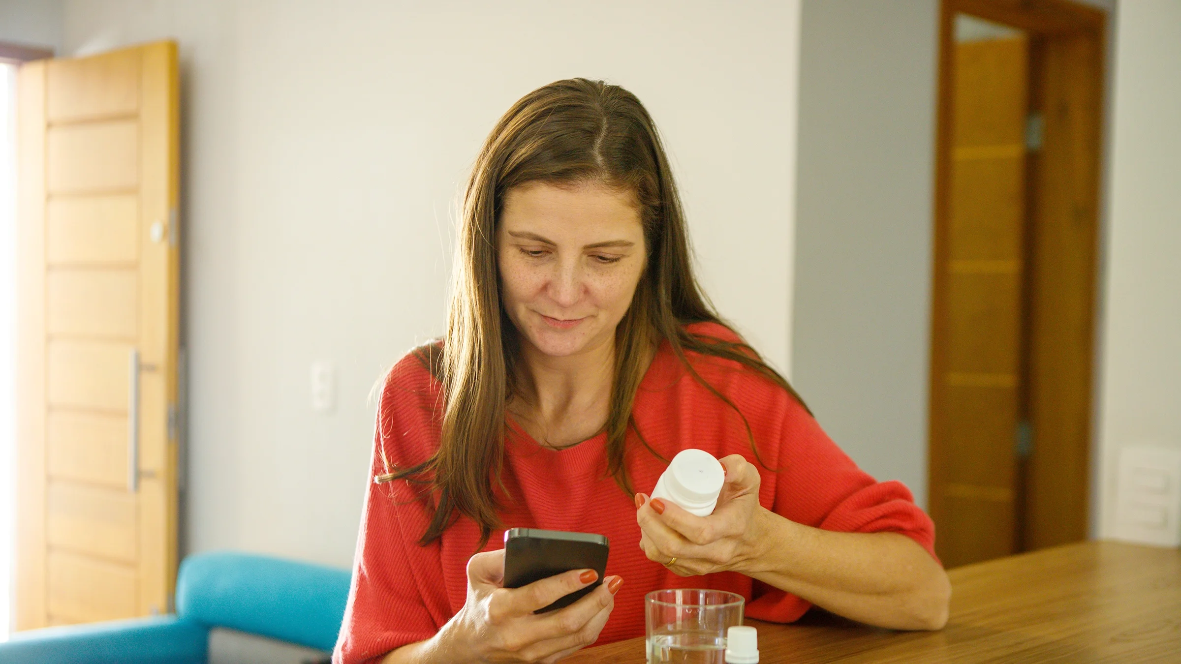 A woman reads the label of a medicine bottle.