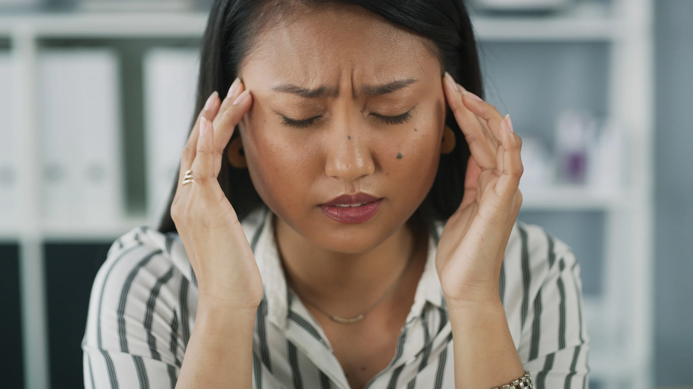 A person with a headache rubbing their temples.