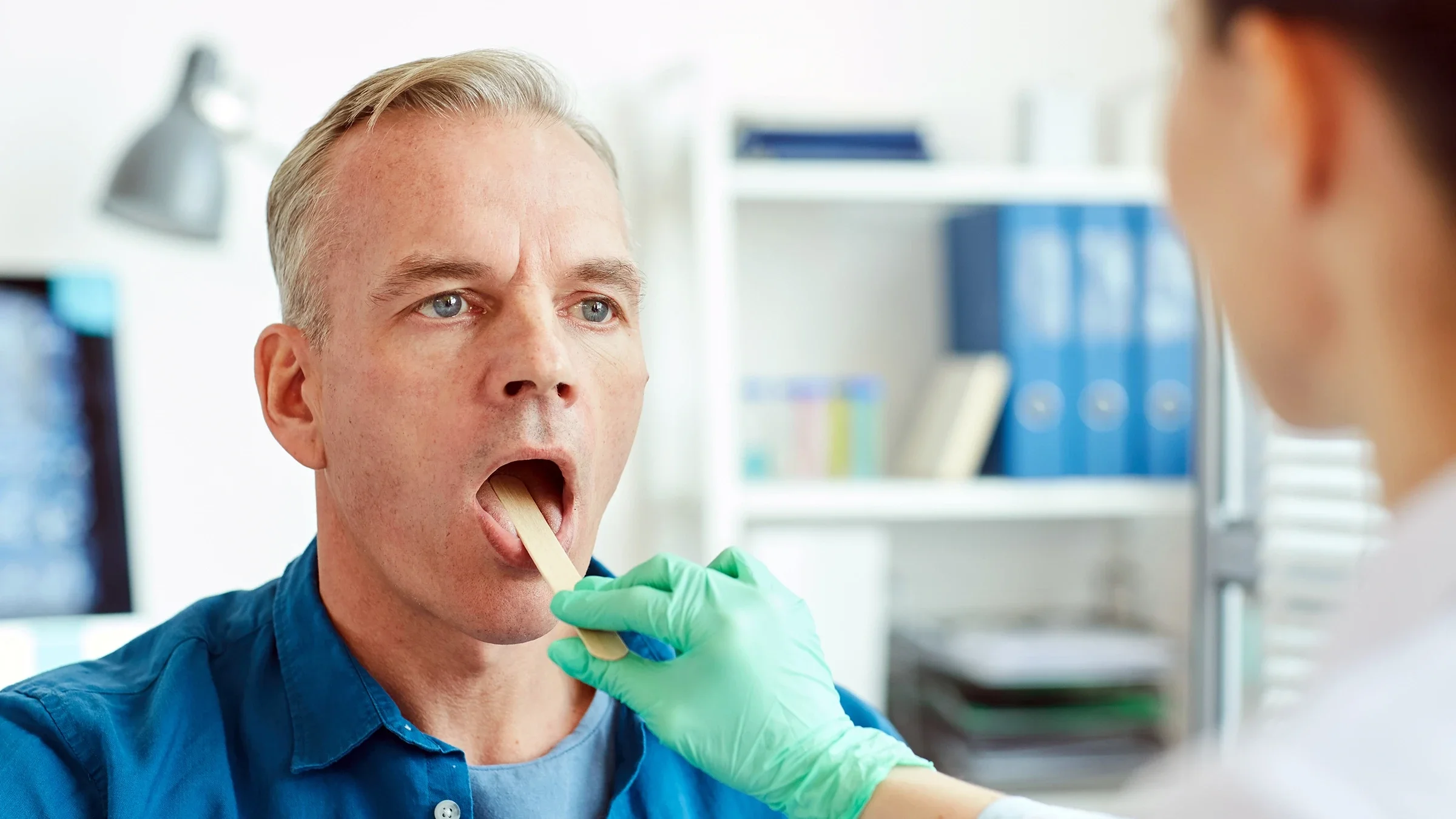 A man opens his mouth during a throat examination.