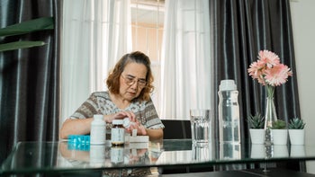 heart-failure: senior woman placing medication in pill organizer 1284725620