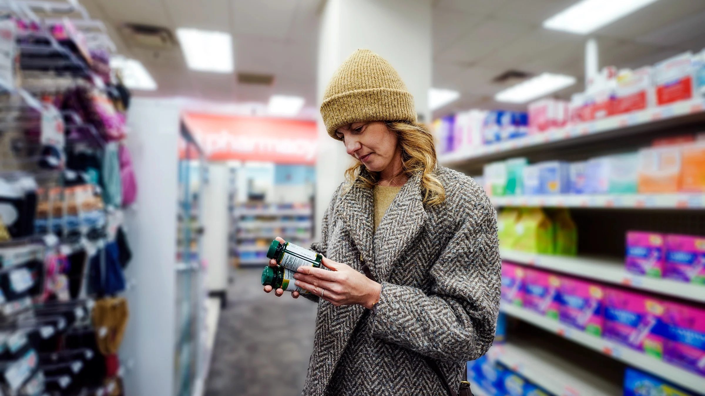 A woman looks at vitamin and supplement bottles at a pharmacy.