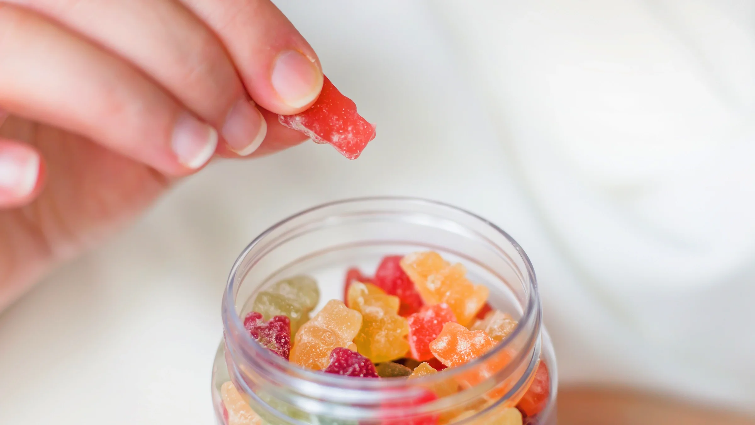 Close-up hand holding a jar of gummy vitamins.