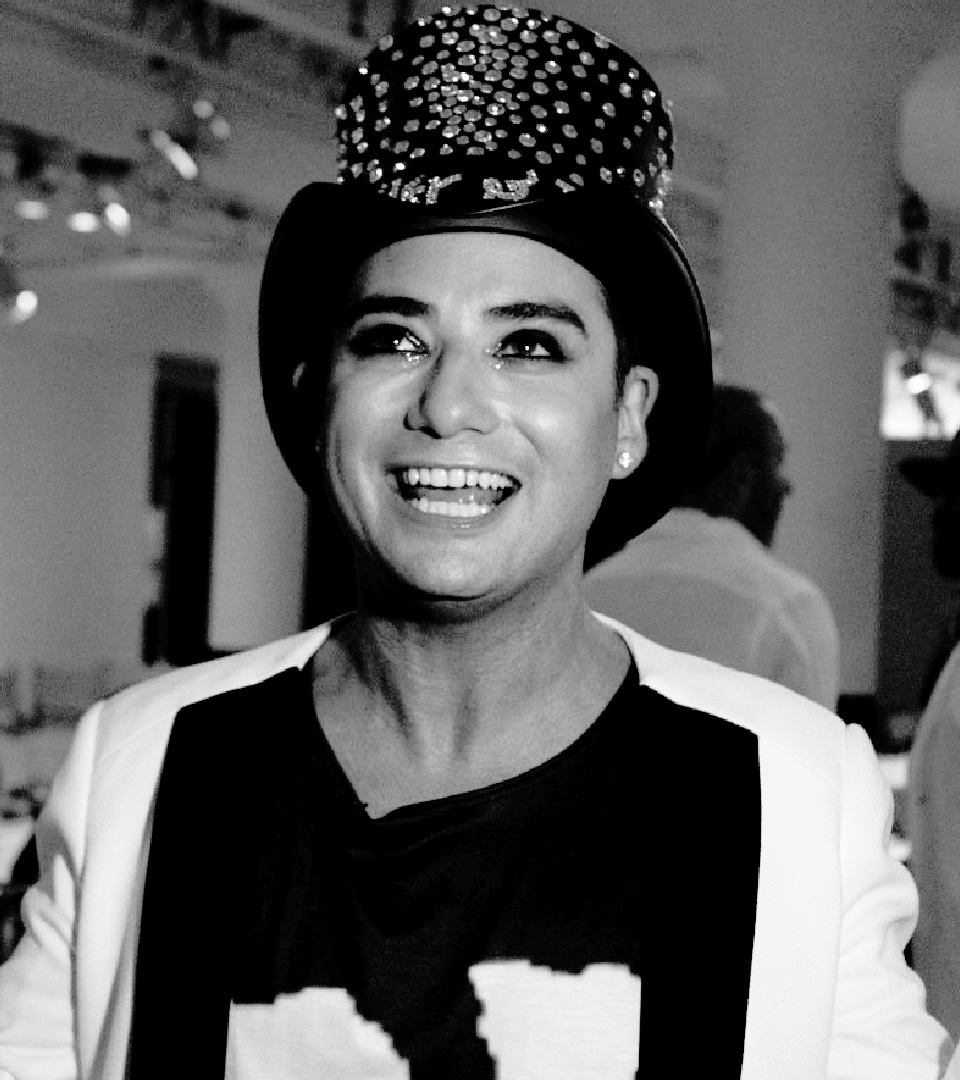 Black and white photo of Michael Kuluva smiling with a big hat on.
