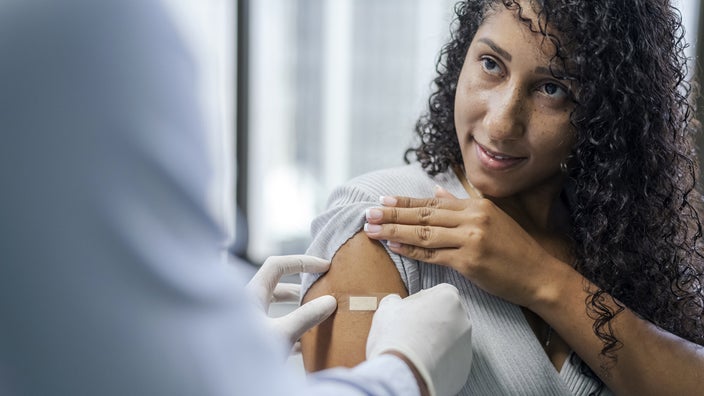 A healthcare professional fastens a Band-Aid on a woman’s arms after she received a vaccine.